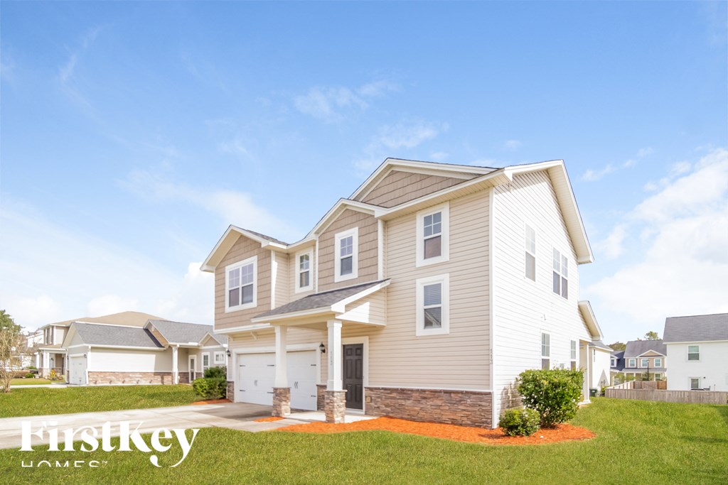 a beige house with white siding and a driveway