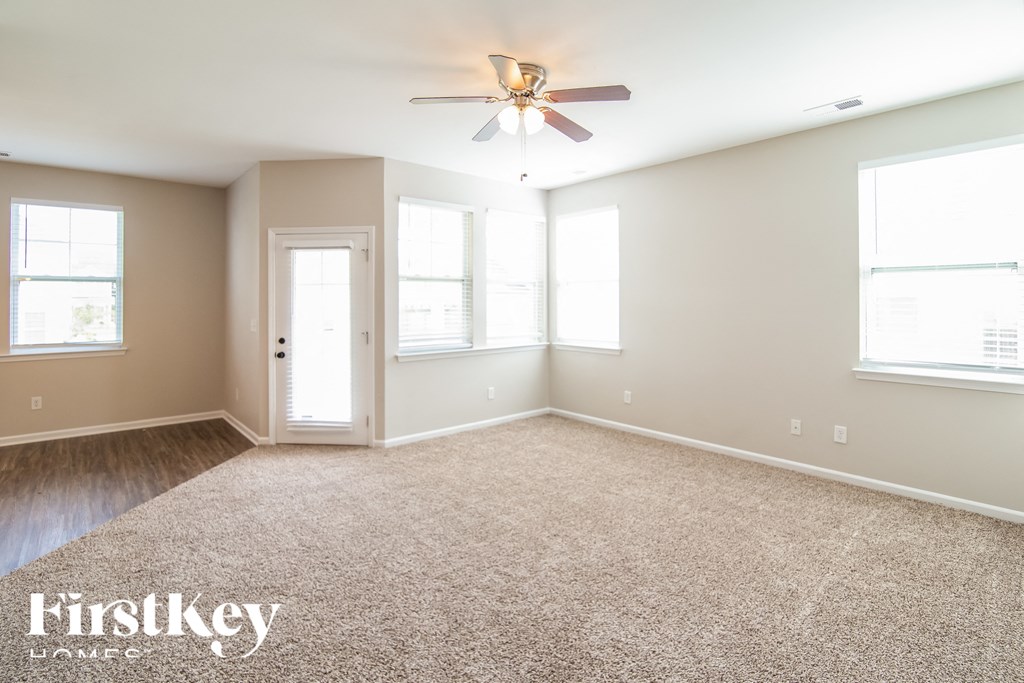 a empty living room with a ceiling fan and a carpet