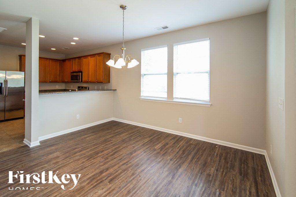 an empty living room with wood flooring and a kitchen
