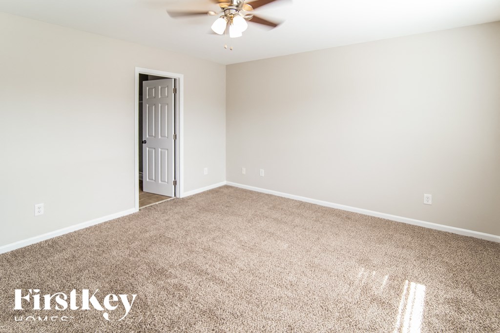 a empty living room with carpet and a ceiling fan