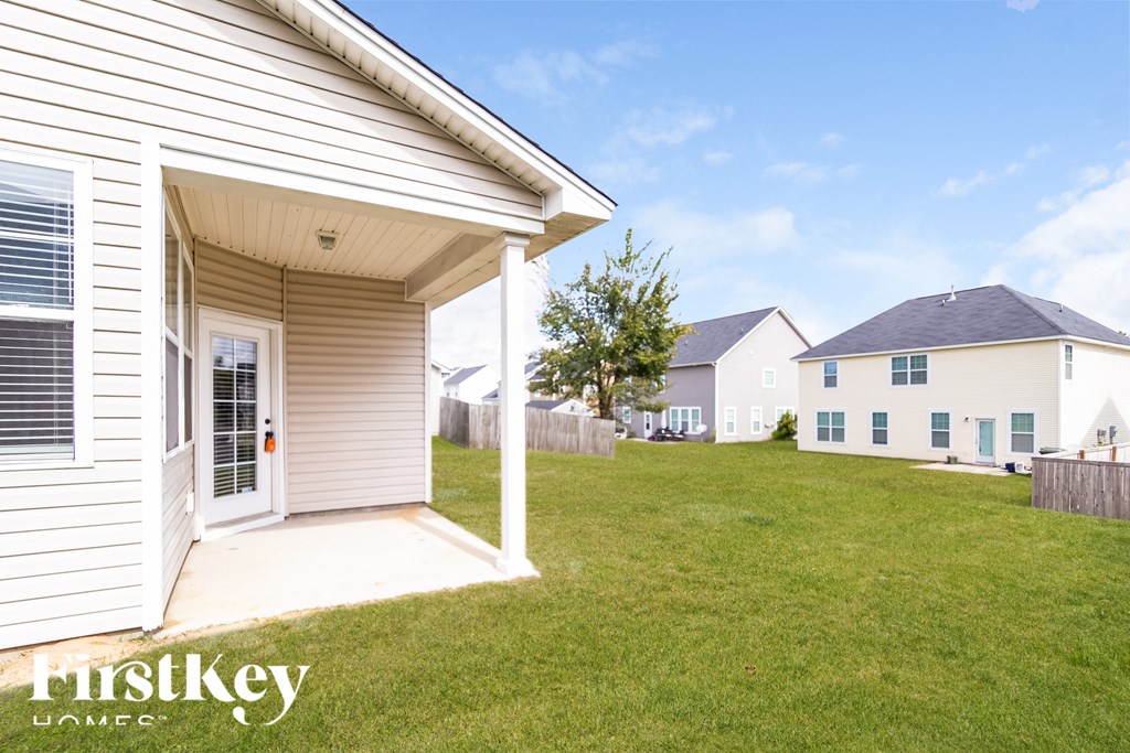 the backyard of a white house with a yard and a garage