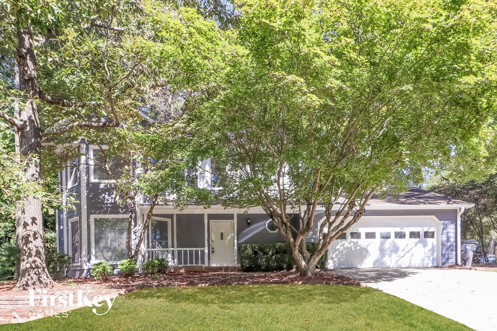 A house with a white door and a tree in front.