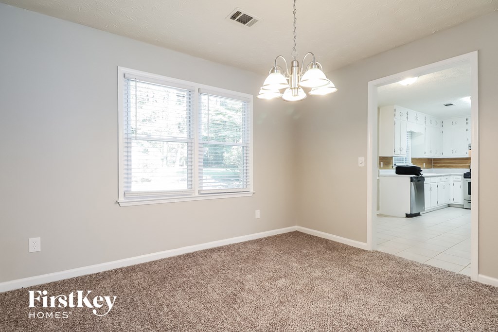 A room with a carpeted floor and a chandelier hanging from the ceiling.