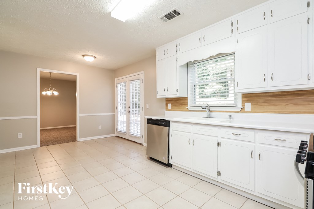 A kitchen with white cabinets and a dishwasher.
