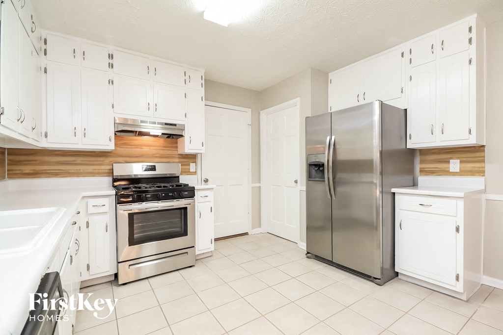 A kitchen with white cabinets and appliances.