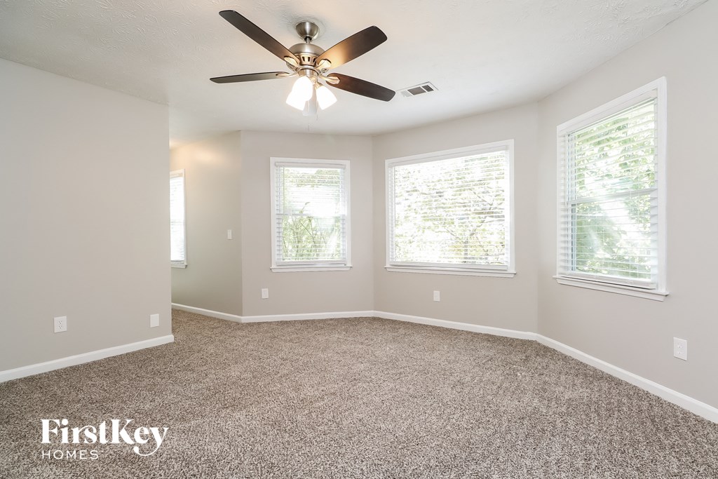A spacious room with a ceiling fan and carpeted floor.