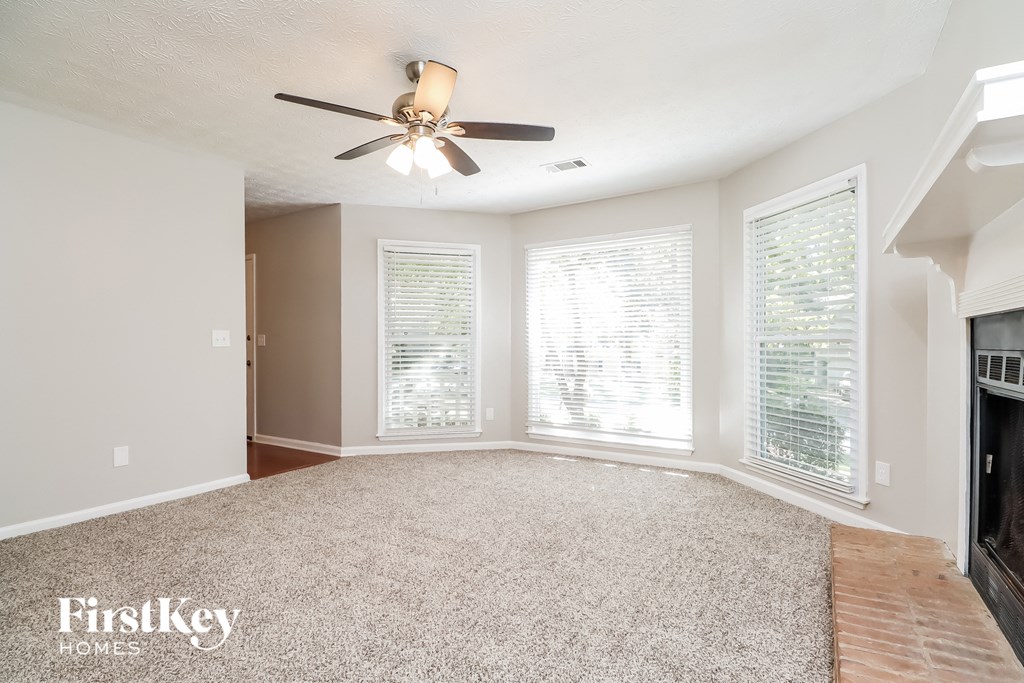 A spacious room with a ceiling fan and carpeted floor.