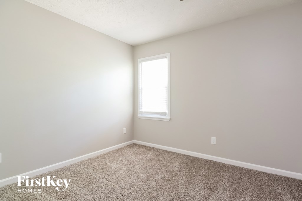 A room with a carpeted floor and a window letting in light.