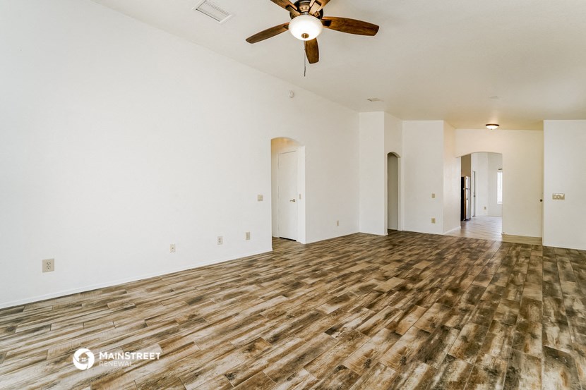 an empty living room with a ceiling fan and white walls