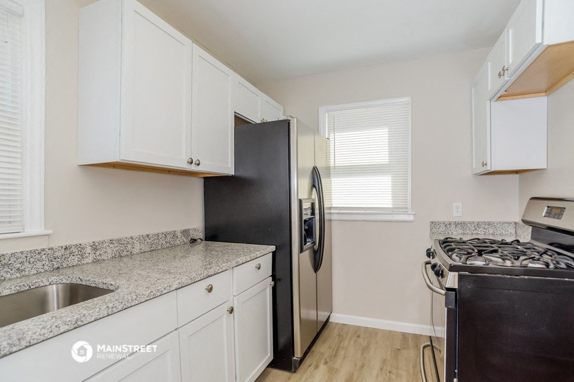 a kitchen with white cabinets and a black refrigerator and a stove