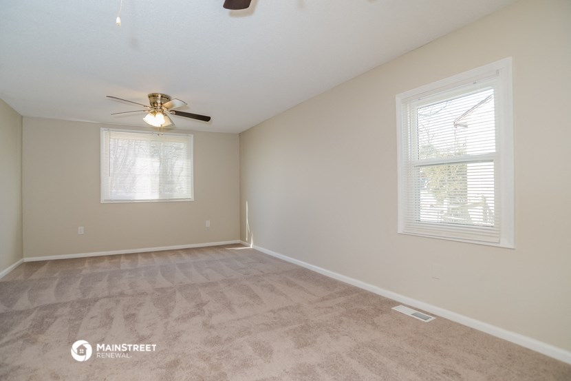 the spacious living room with carpeting and a ceiling fan