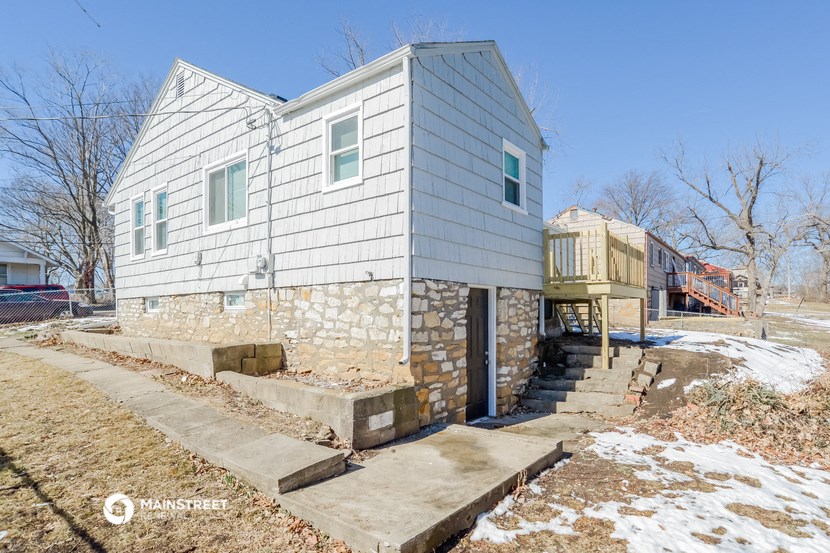 a white house with a stone wall and stairs in front of it