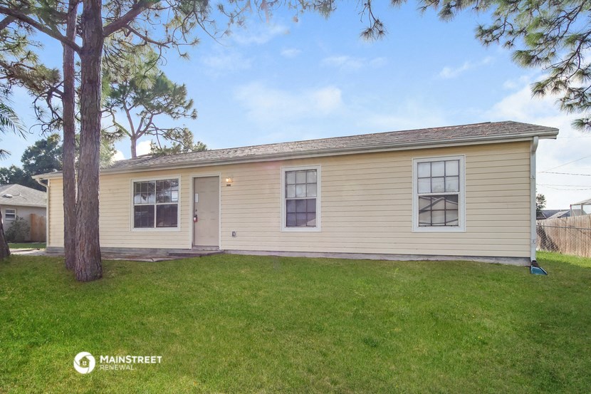 a small yellow house with a yard and a tree