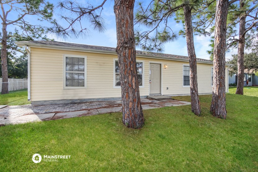 a yellow house with three pine trees in front of it