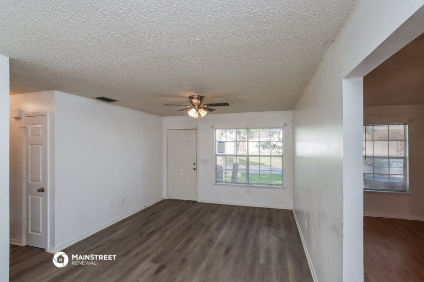 the living room of an empty house with a ceiling fan