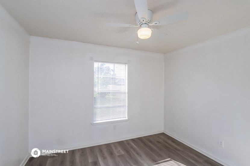 a bedroom with white walls and a ceiling fan