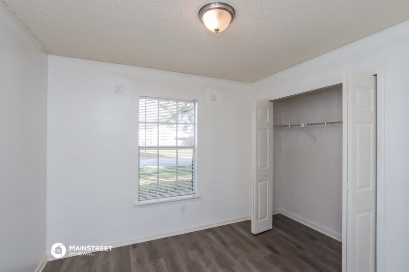 the living room of an apartment with a window and a closet
