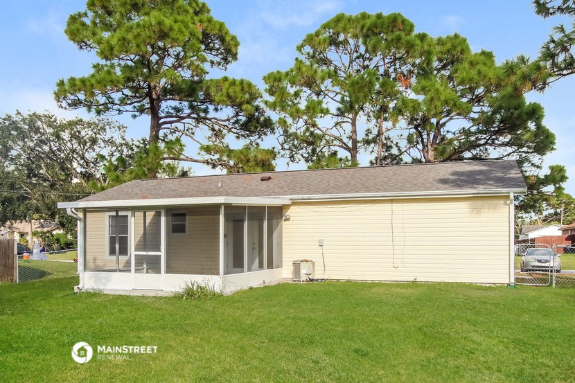 the front of a yellow house with a lawn and trees