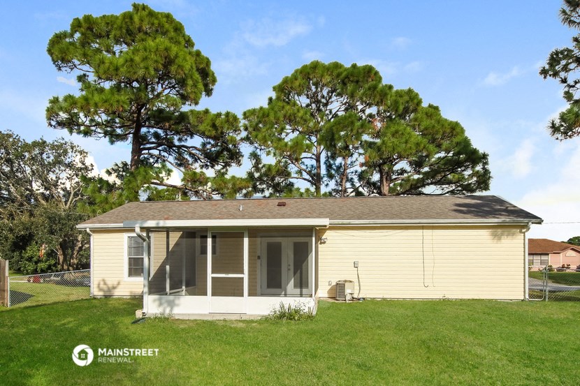 a small yellow house with a lawn and trees behind it