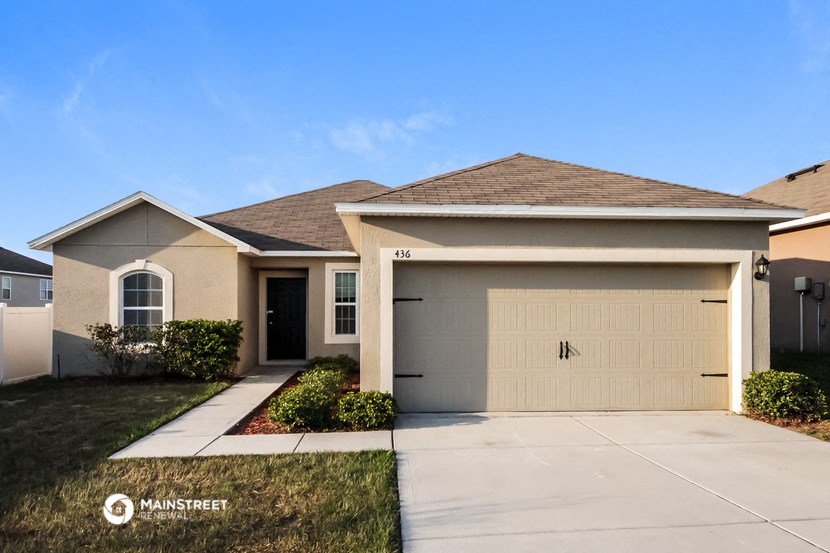 a beige house with a garage door and lawn