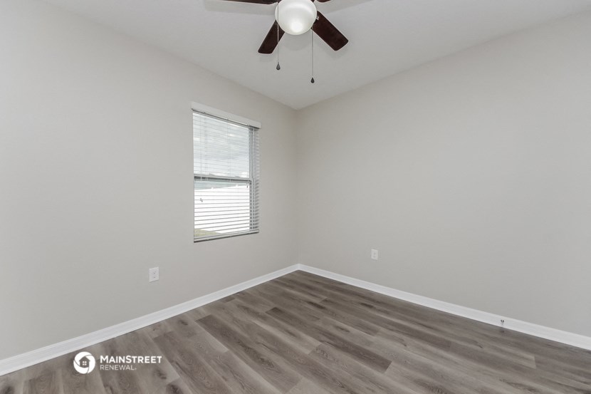 the bedroom has a large window and a ceiling fan