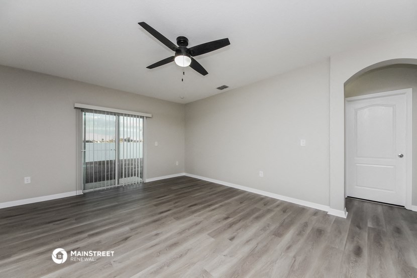 an empty living room with a ceiling fan and a window