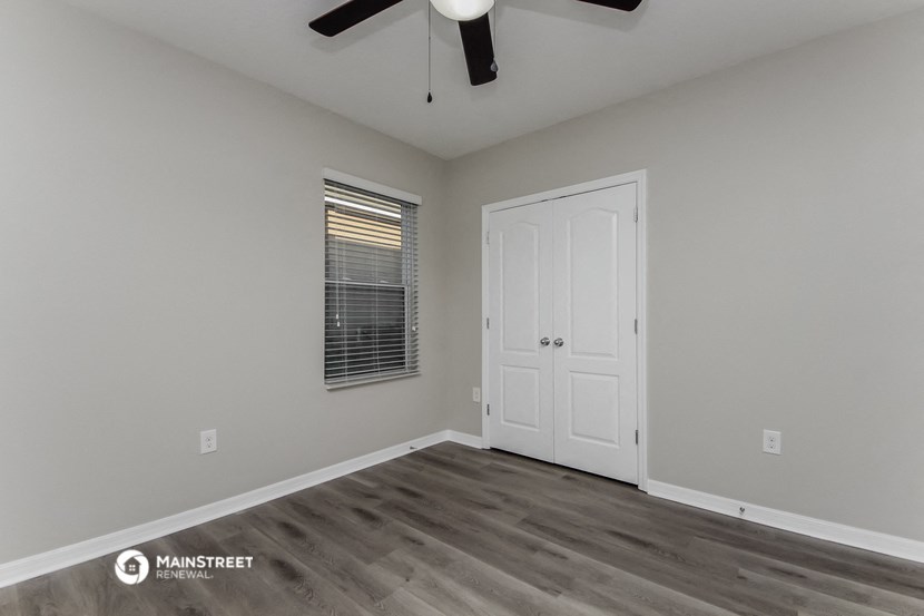 the living room of a 2020 manufactured home with a ceiling fan and a white door