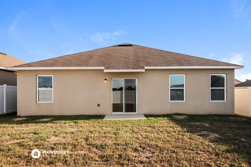 a beige house with a grass yard and a blue sky
