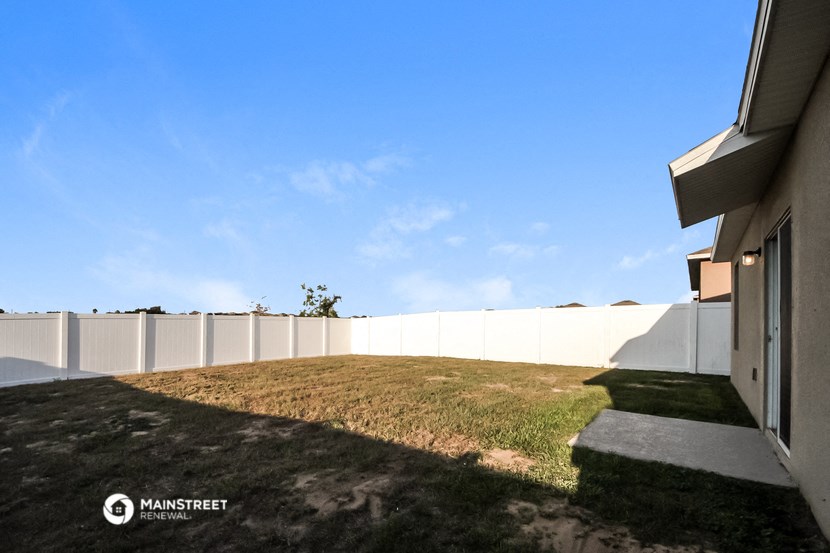 a view of the yard of a house with a fence and grass