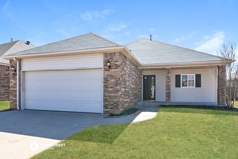 a brick house with a white garage door and a lawn