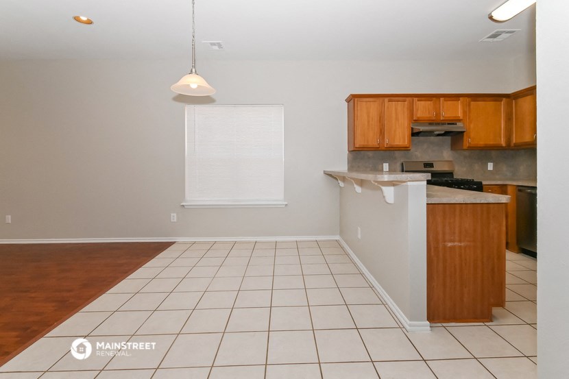 an empty kitchen with a white tile floor and wooden cabinets