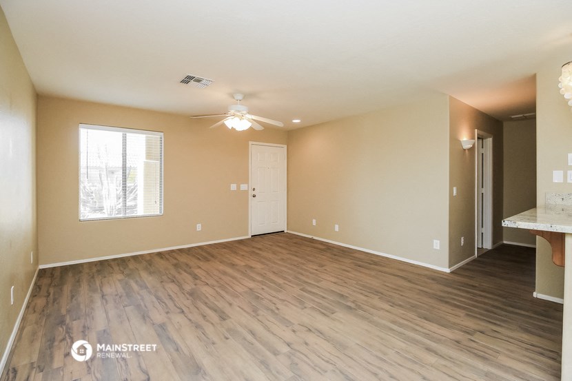 an empty living room with wood flooring and a ceiling fan