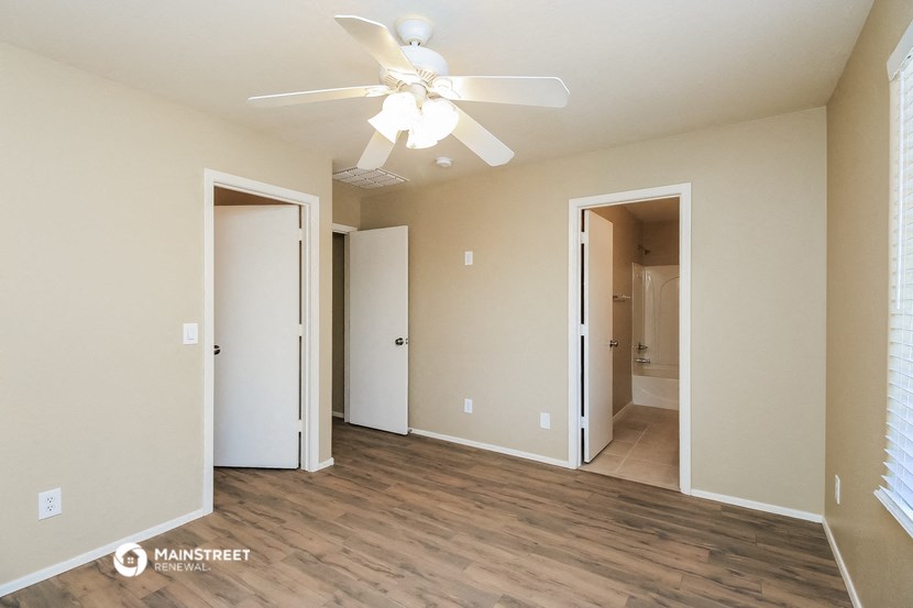 a living room with a ceiling fan and a door to a hallway