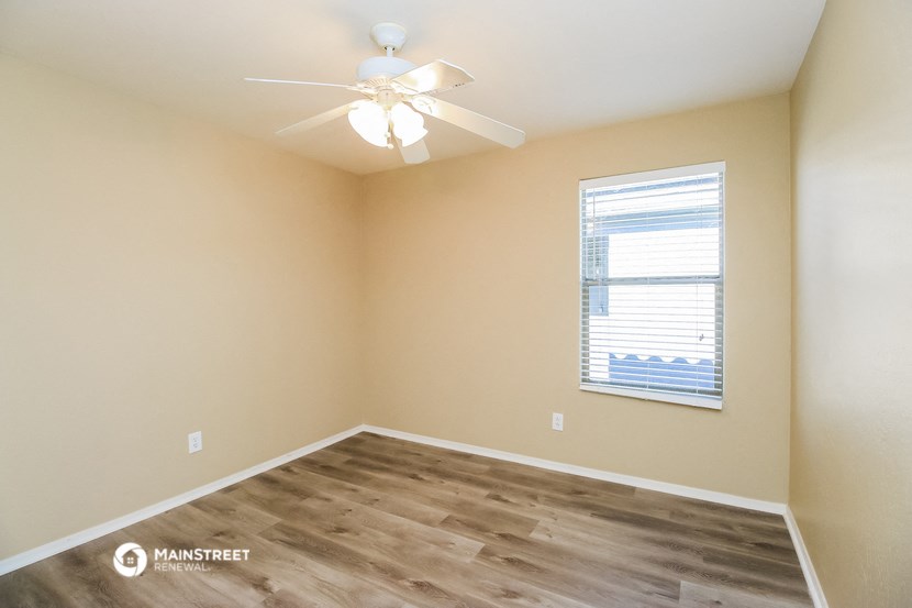 an empty room with a ceiling fan and a window