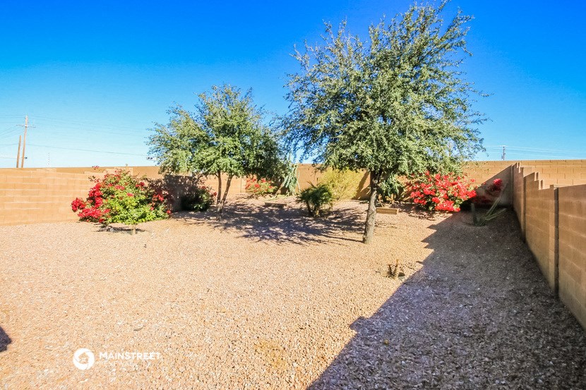 a backyard with trees and flowers and a fence