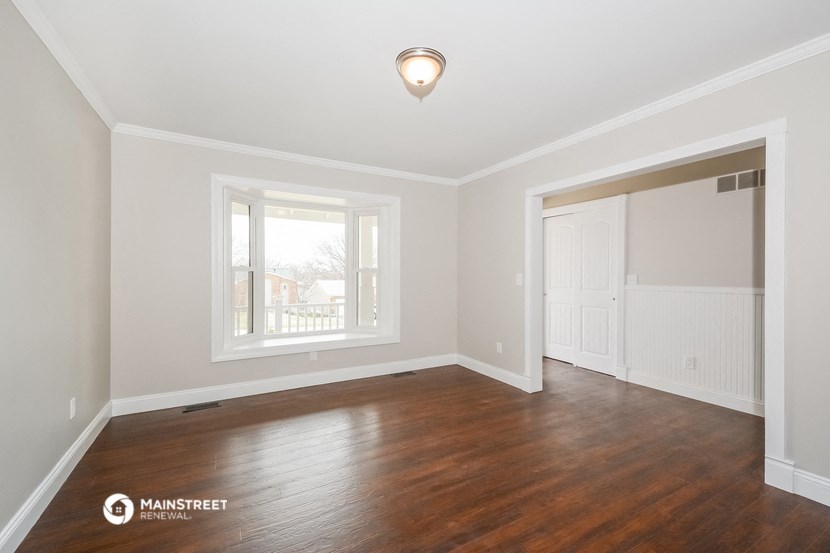the living room of an empty house with wood flooring and a window