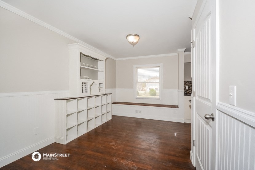 a dining room with white cabinets and a window