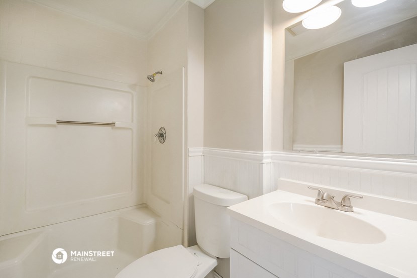 a white bathroom with a sink and toilet and a shower