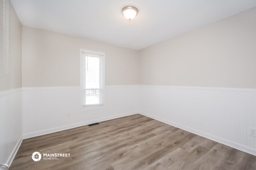 the spacious living room with wood flooring and white walls