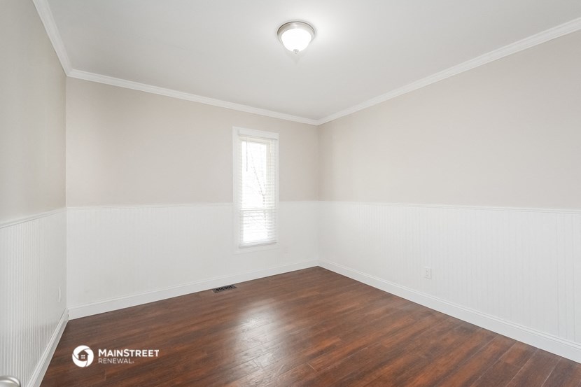 an empty room with white walls and wood floors and a window