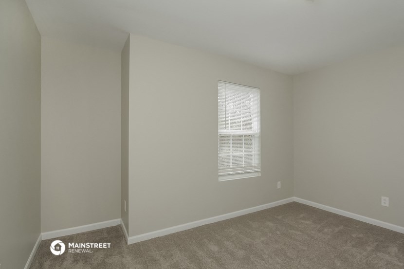 a bedroom with a window and a carpeted floor