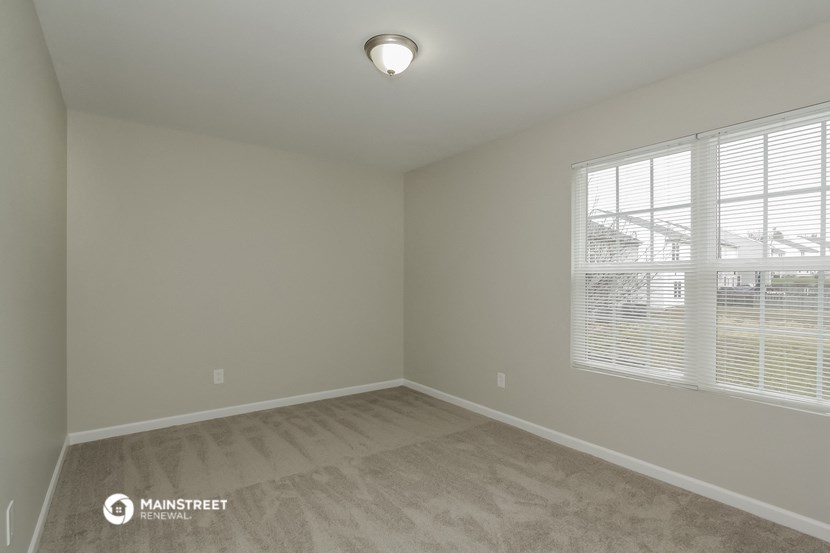 the spacious living room with two windows and wood flooring