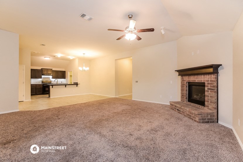 the living room is spacious with a fireplace and carpeted flooring