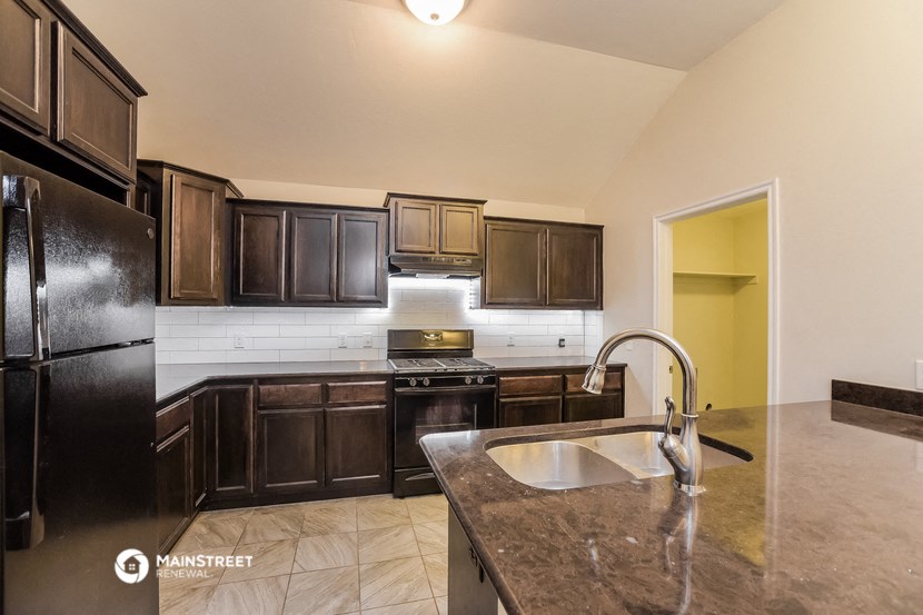 a kitchen with dark wood cabinets and granite counter tops and a sink