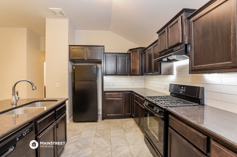 a kitchen with dark wood cabinets and a black refrigerator