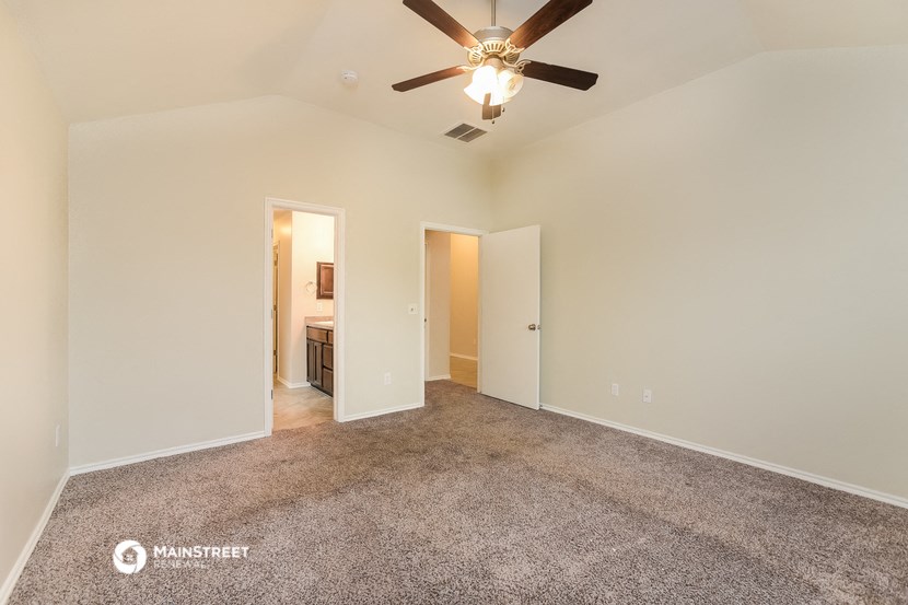 the spacious living room with carpet and ceiling fan