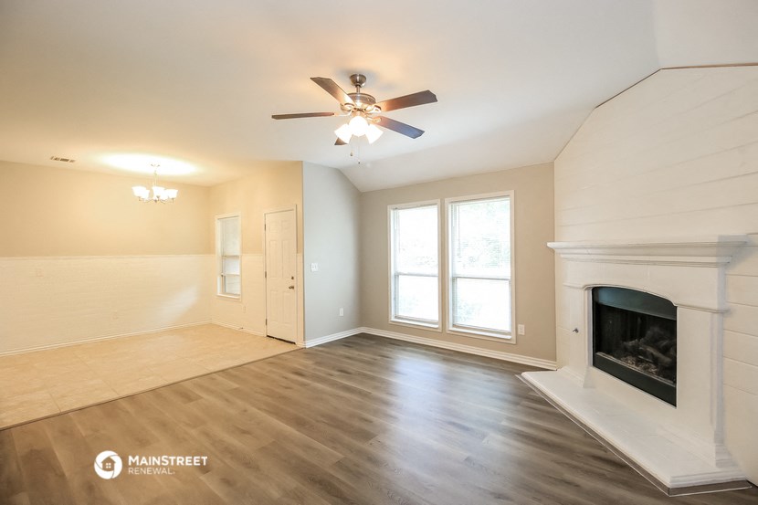 a living room with a fireplace and a ceiling fan