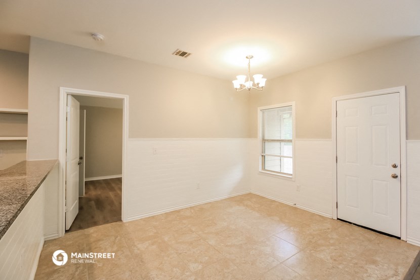 a empty dining room with a white door and a window