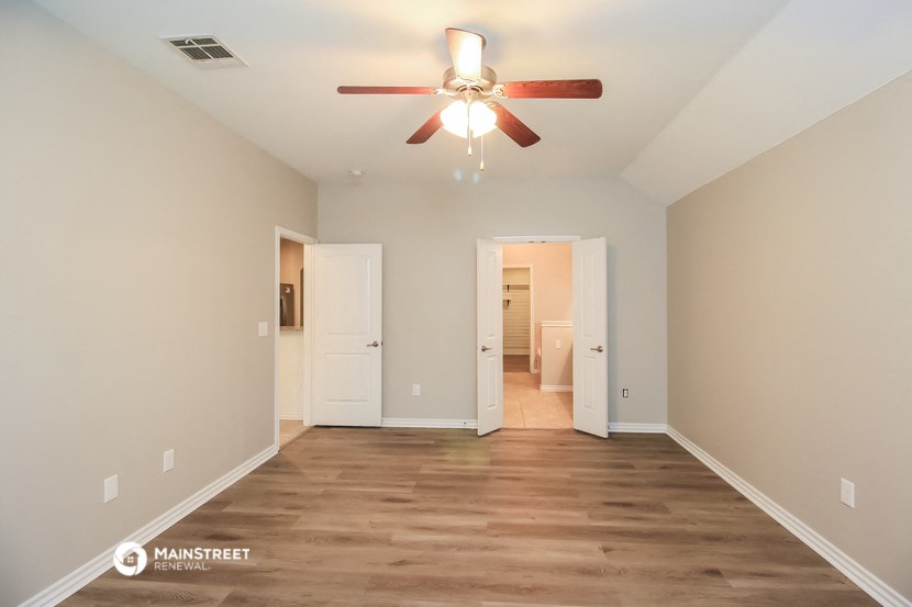 a spacious living room with a ceiling fan and wood floors