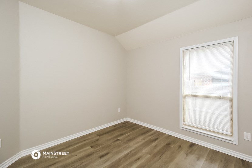 a bedroom with wood flooring and a window